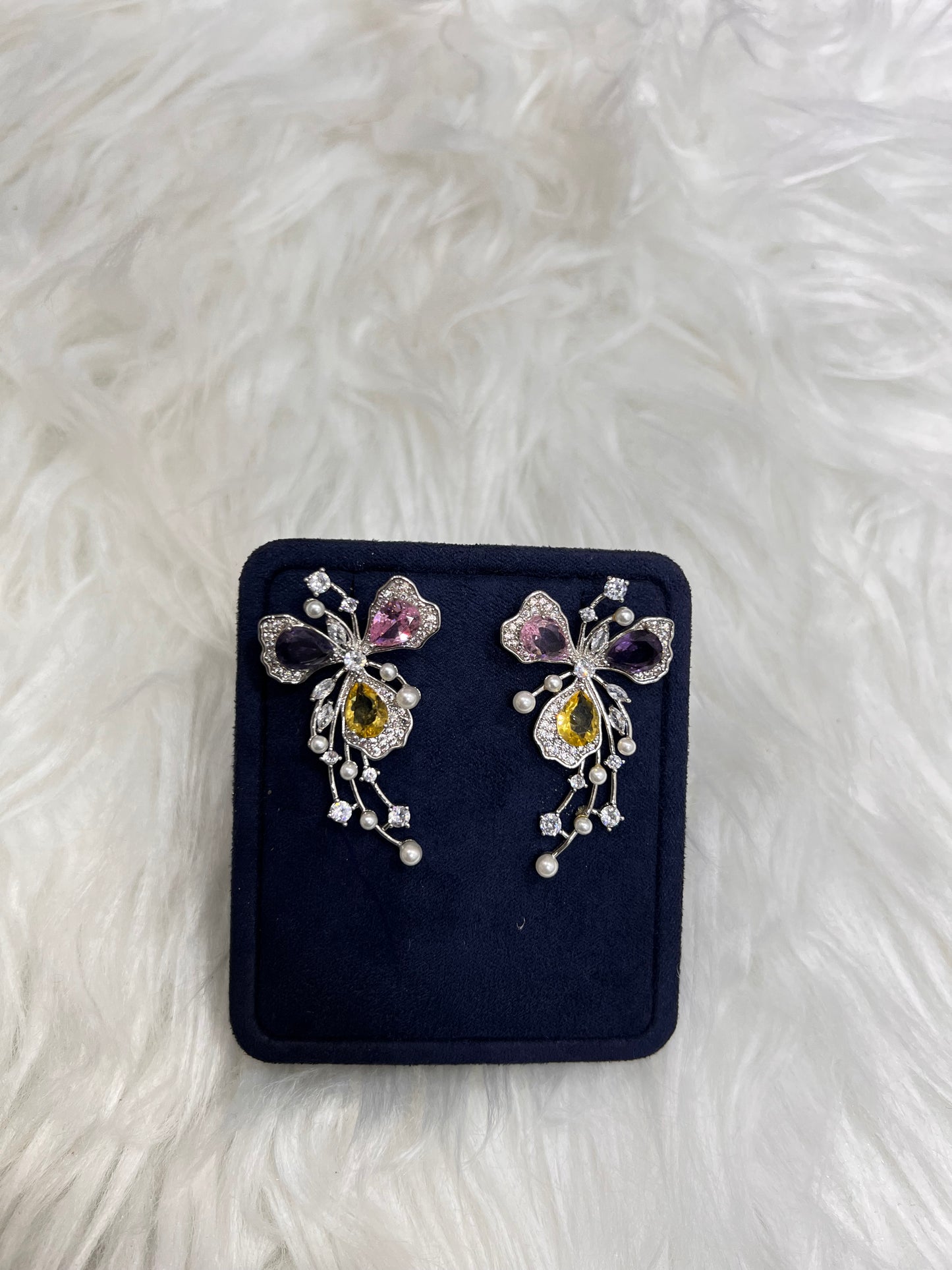 A pair of silver butterfly-shaped earrings with purple, yellow, and pink gemstones, Perfect for vibrant bridal parties, spring galas, or as a uniquely personal statement piece.