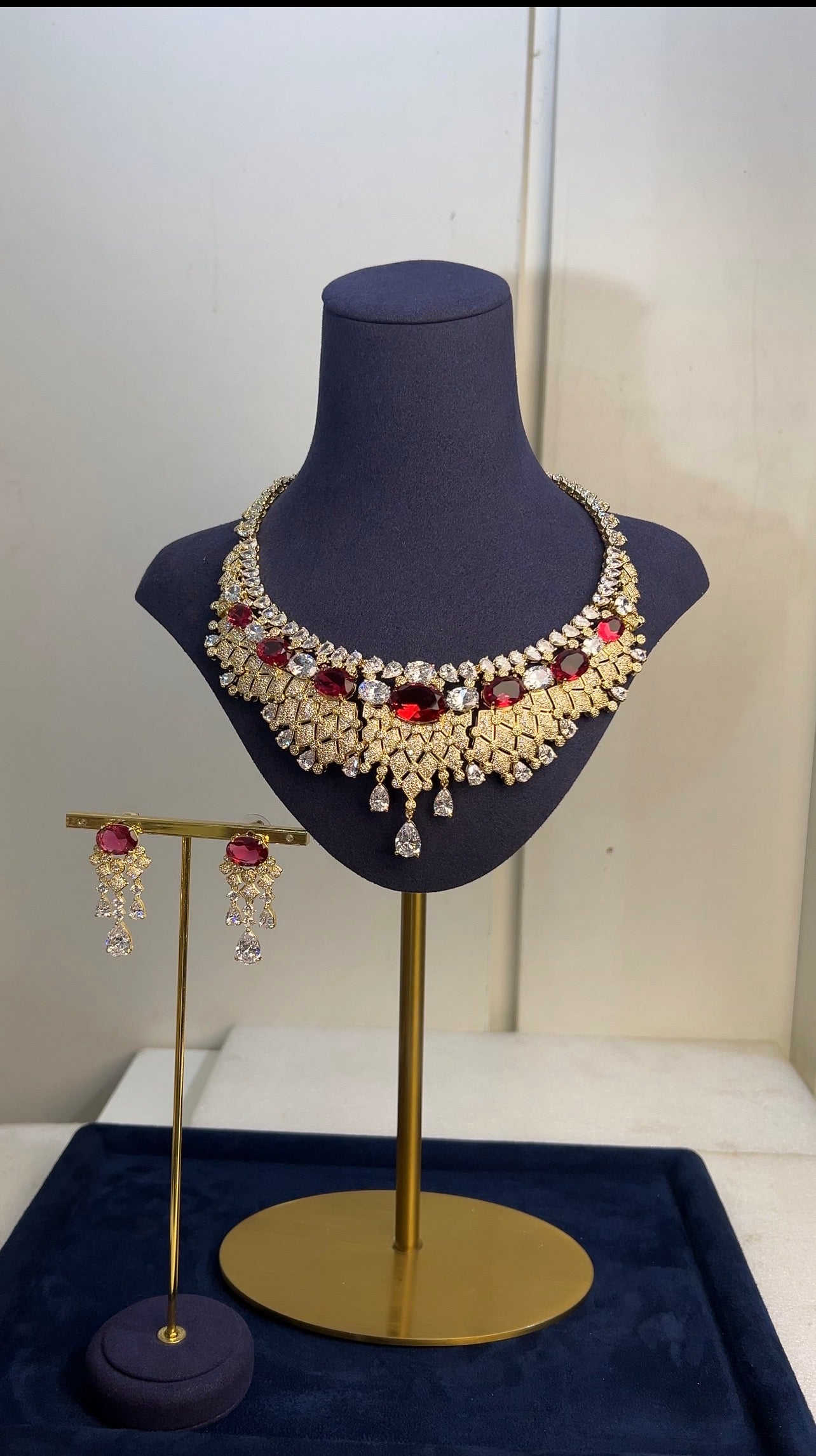 Jewelry set including a necklace and earrings on a mannequin bust and stand.