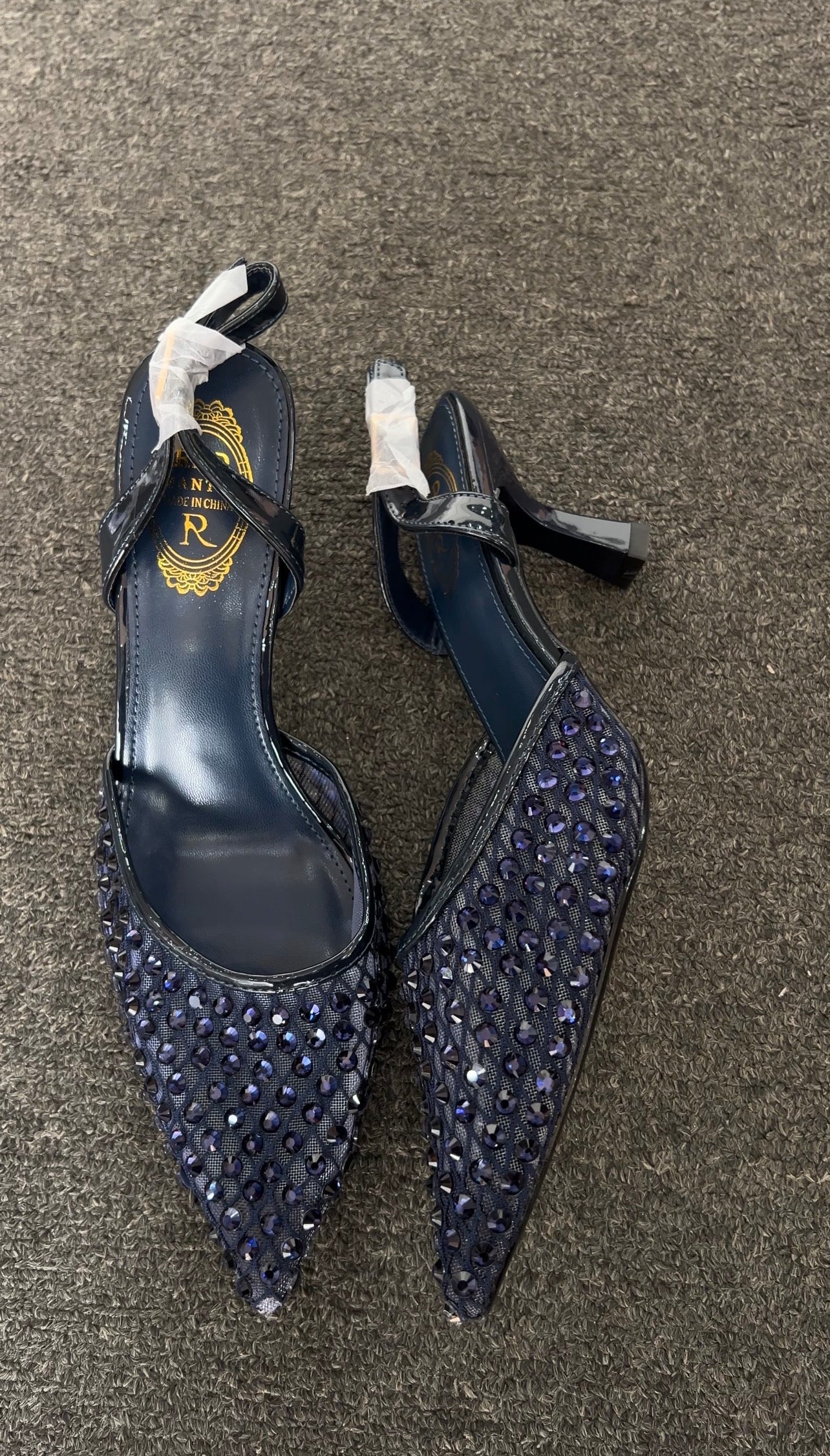 High-heeled shoes with sequin details on Featuring a contemporary sheer mesh upper, these heels are meticulously embellished with a grid of tonal navy studs that offer a subtle, sophisticated shimmer