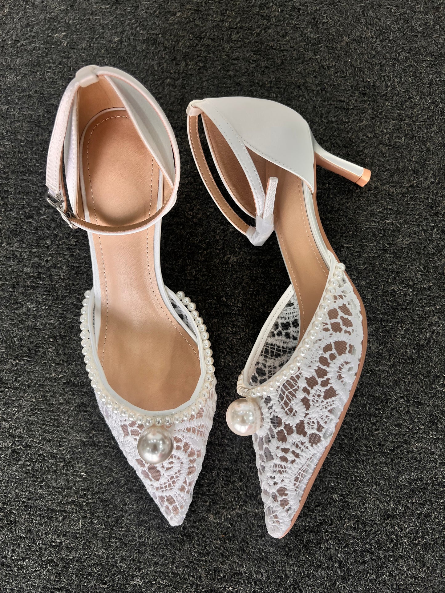 Pair of white lace-up high-heeled shoes with pearl embellishments