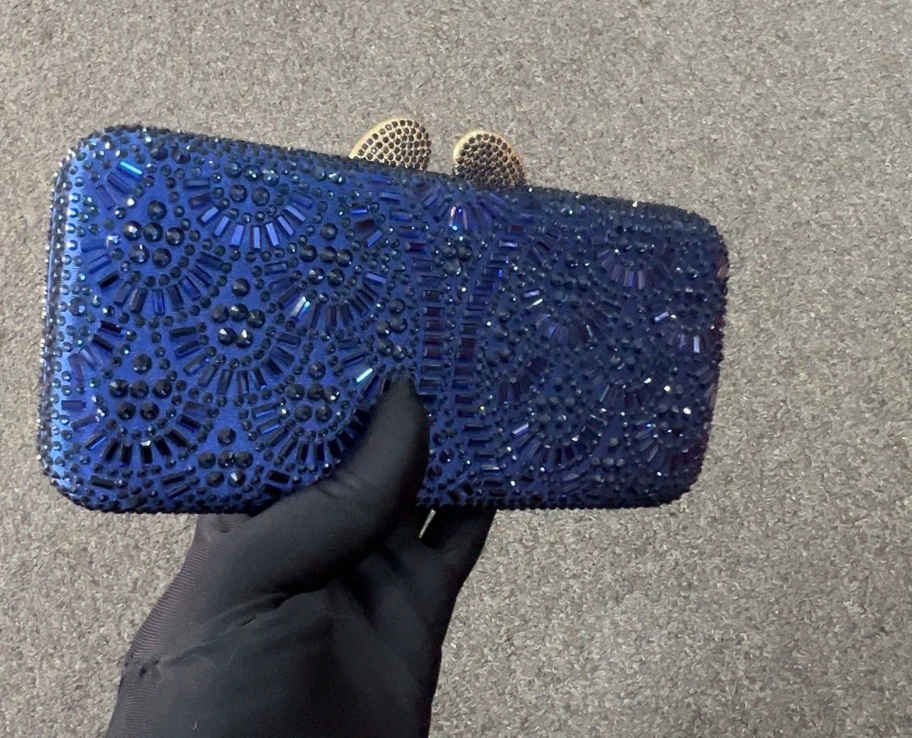 A royal blue beaded clutch purse with intricate circular patterns of rhinestones and beads