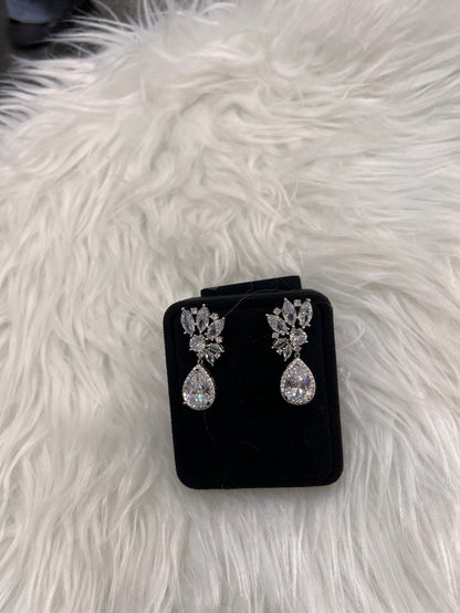 A pair of silver-toned dangle earrings with clear teardrop and floral stones, The ultimate finishing touch for an unforgettable bridal look.