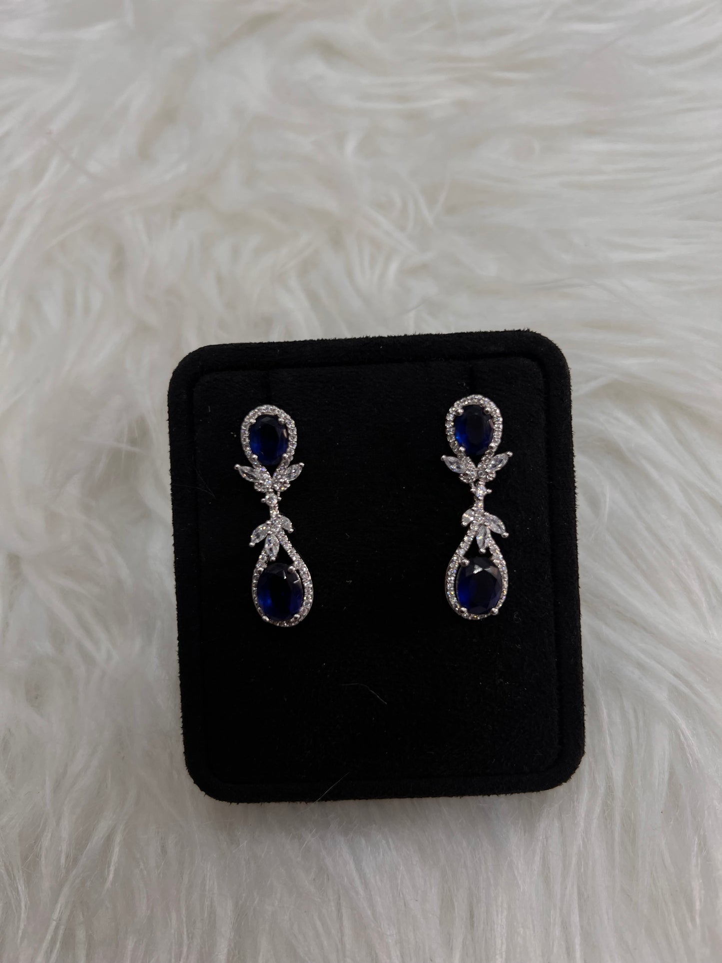 A pair of silver drop earrings with deep blue teardrop-shaped stones and small clear crystal accents, these drops dance beautifully with every turn of the head, offering a classic "something blue" for the traditional bride or a striking pop of color for an evening gown.