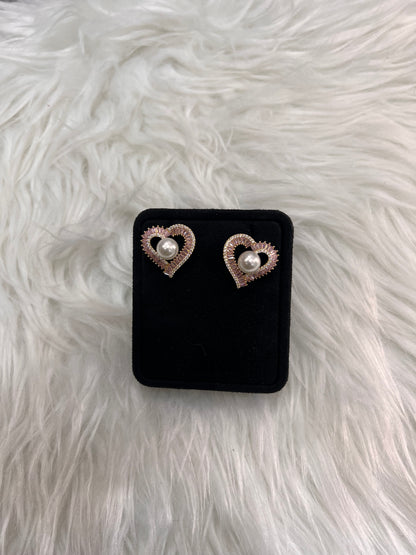 A pair of heart-shaped stud earrings with white pearl centers and rose gold textured borders,  A beautiful, feminine addition to any bridesmaid attire or date-night ensemble.