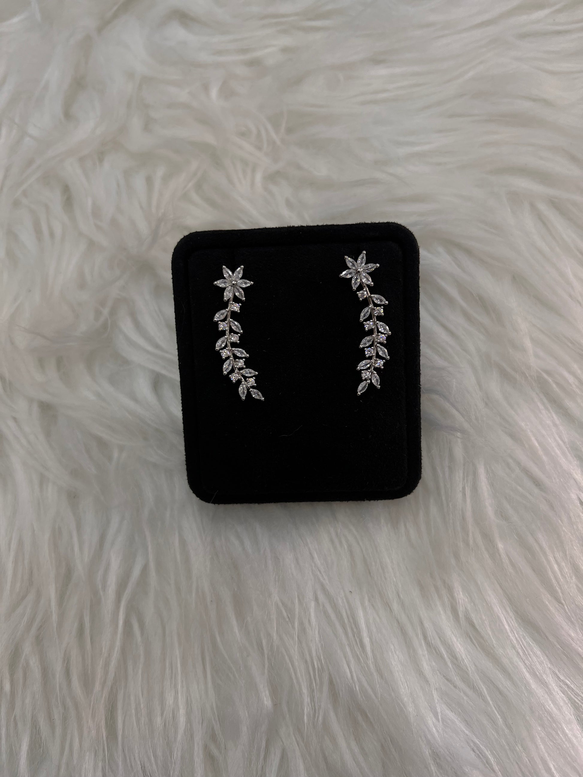 A pair of silver floral and leaf stud earrings.  they offer a high-impact sparkle that beautifully frames the face with effortless grace.