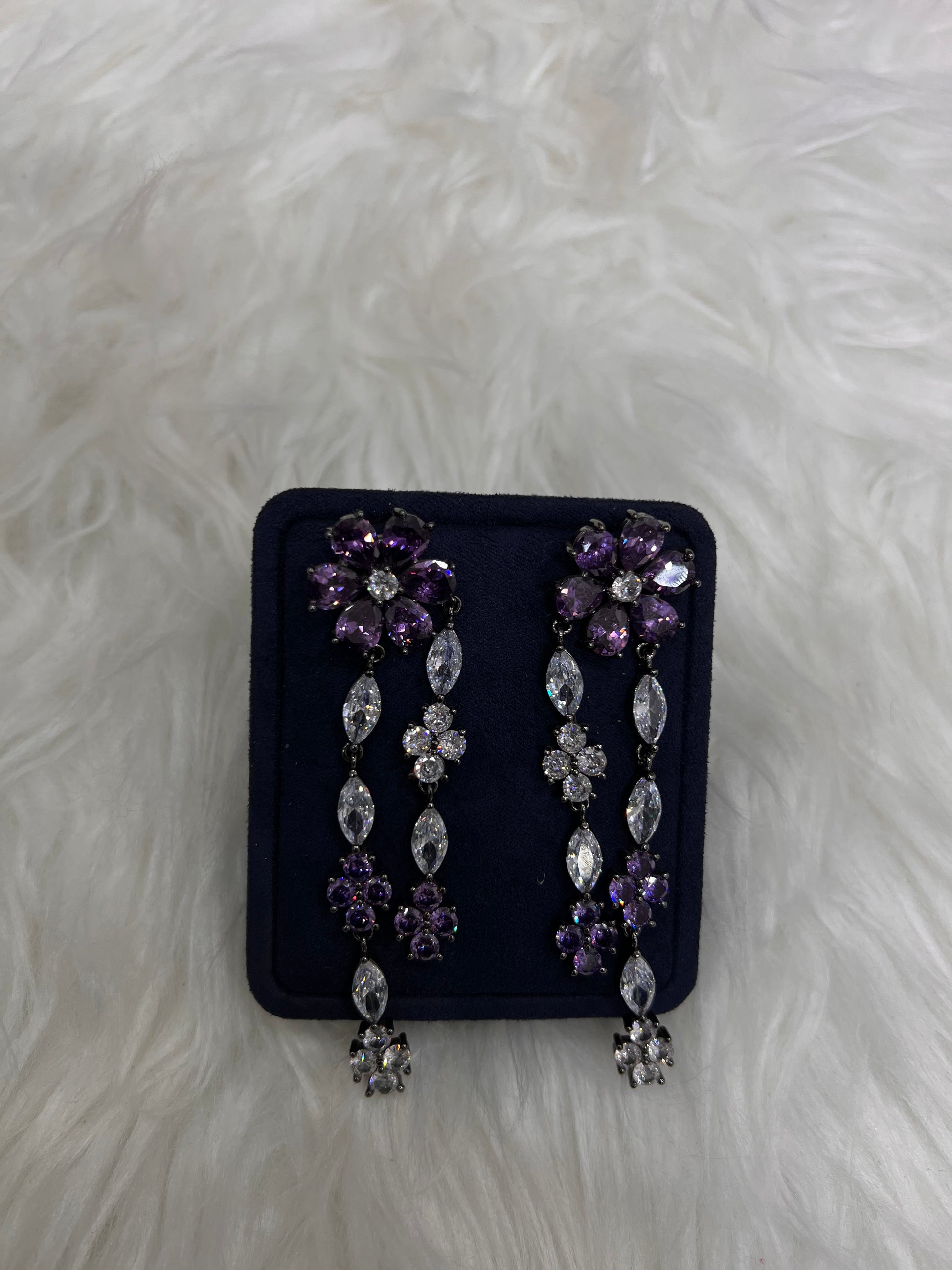 A pair of silver-toned statement earrings with purple and clear rhinestones, perfect for black-tie events, royal-inspired bridal looks, or a dramatic night out.