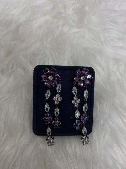 A pair of silver-toned statement earrings with purple and clear rhinestones, perfect for black-tie events, royal-inspired bridal looks, or a dramatic night out.