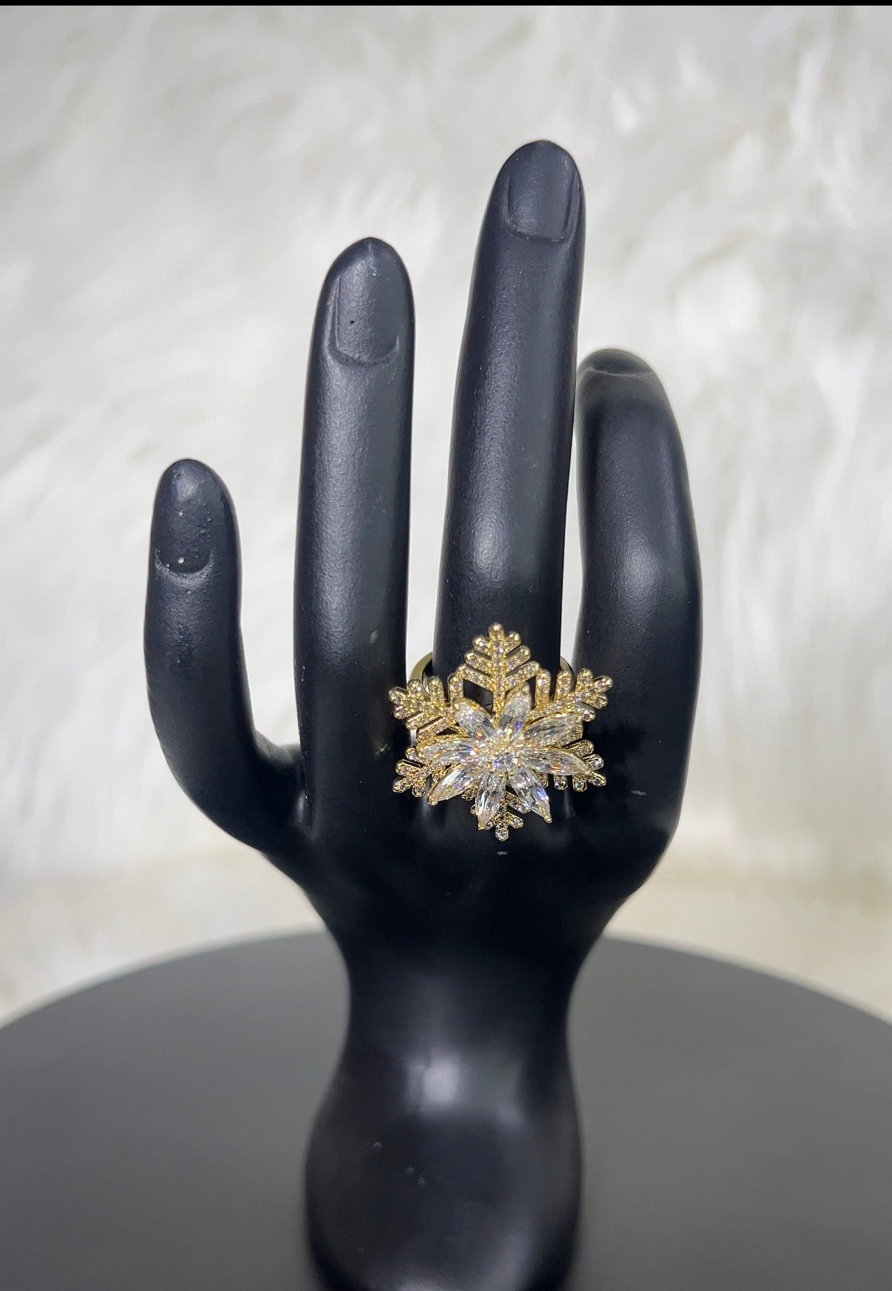 A snowflake-shaped ring with gold-toned metal and clear stones.