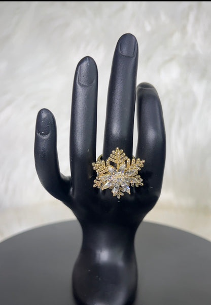 A snowflake-shaped ring with gold-toned metal and clear stones.