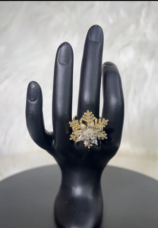 A snowflake-shaped ring with gold-toned metal and clear stones.