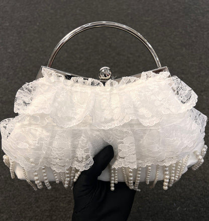 A white lace and ruffle evening clutch bag with pearl fringe, a silver metal frame, and a clear acrylic top frame 