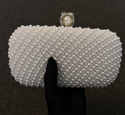 A white pearl-beaded clutch purse with a large central pearl and silver-toned setting