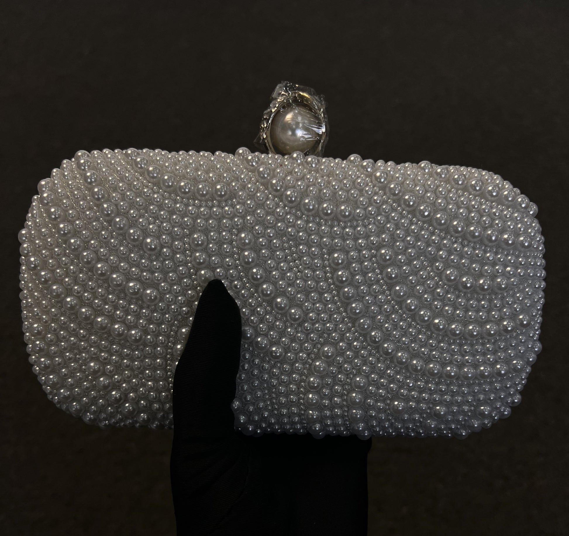  Its sleek shape is elevated by a prominent pearl top clasp, providing a refined, classic look for brides and formal guests.