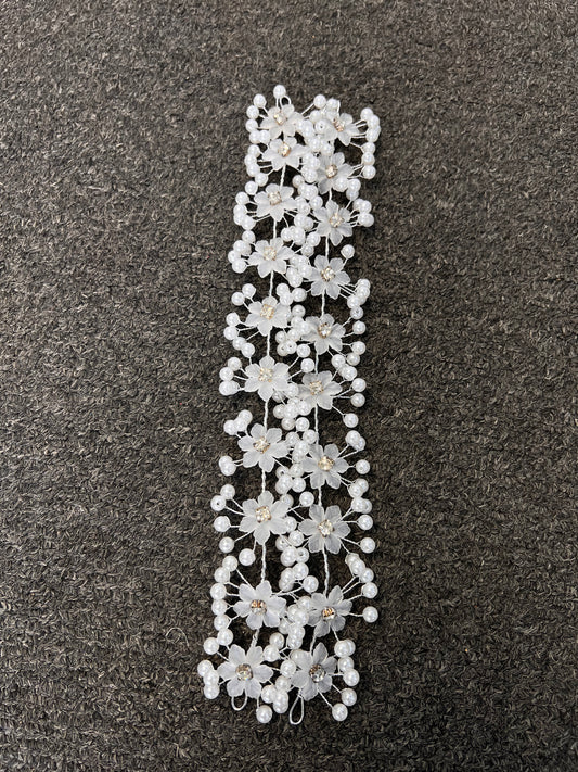 A white floral hair accessory with embroidered flowers, pearl-like beads, and small gold center detail