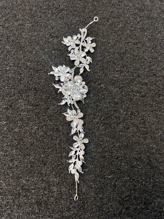 A silver floral hair claw clip with clear rhinestones. Thin, flexible vine design can be easily woven into braids, pinned alongside low buns, or styled as a delicate crown accent.