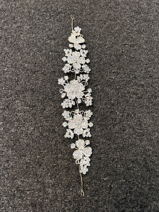 A silver-toned floral hair claw clip with clear rhinestones, Polished silver setting maximizes light reflection for extra sparkle in photos and under venue lighting.