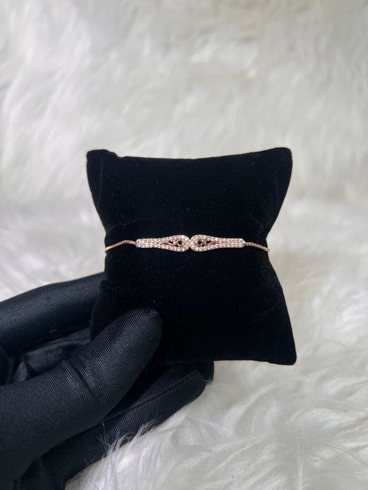 A delicate rose gold bracelet with a double knot design set with small pink gemstones. Wear it alone for a refined accent or layer it with your favorite watch for an elevated look.