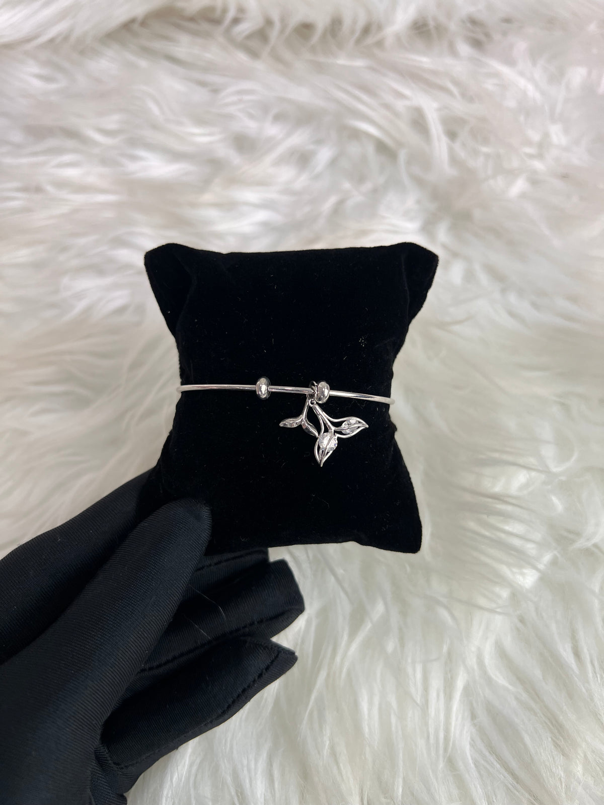A silver bangle bracelet with a small bird charm