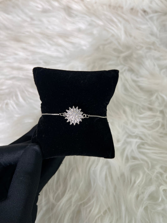 A delicate silver-toned bracelet with a sparkling starburst or sunflower-shaped centerpiece.