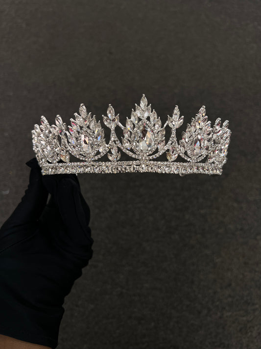 A sparkling silver rhinestone tiara with five ornate leaf-like peaks, Best For: Modern glamorous brides, dramatic updos, and high-neck formal gowns.