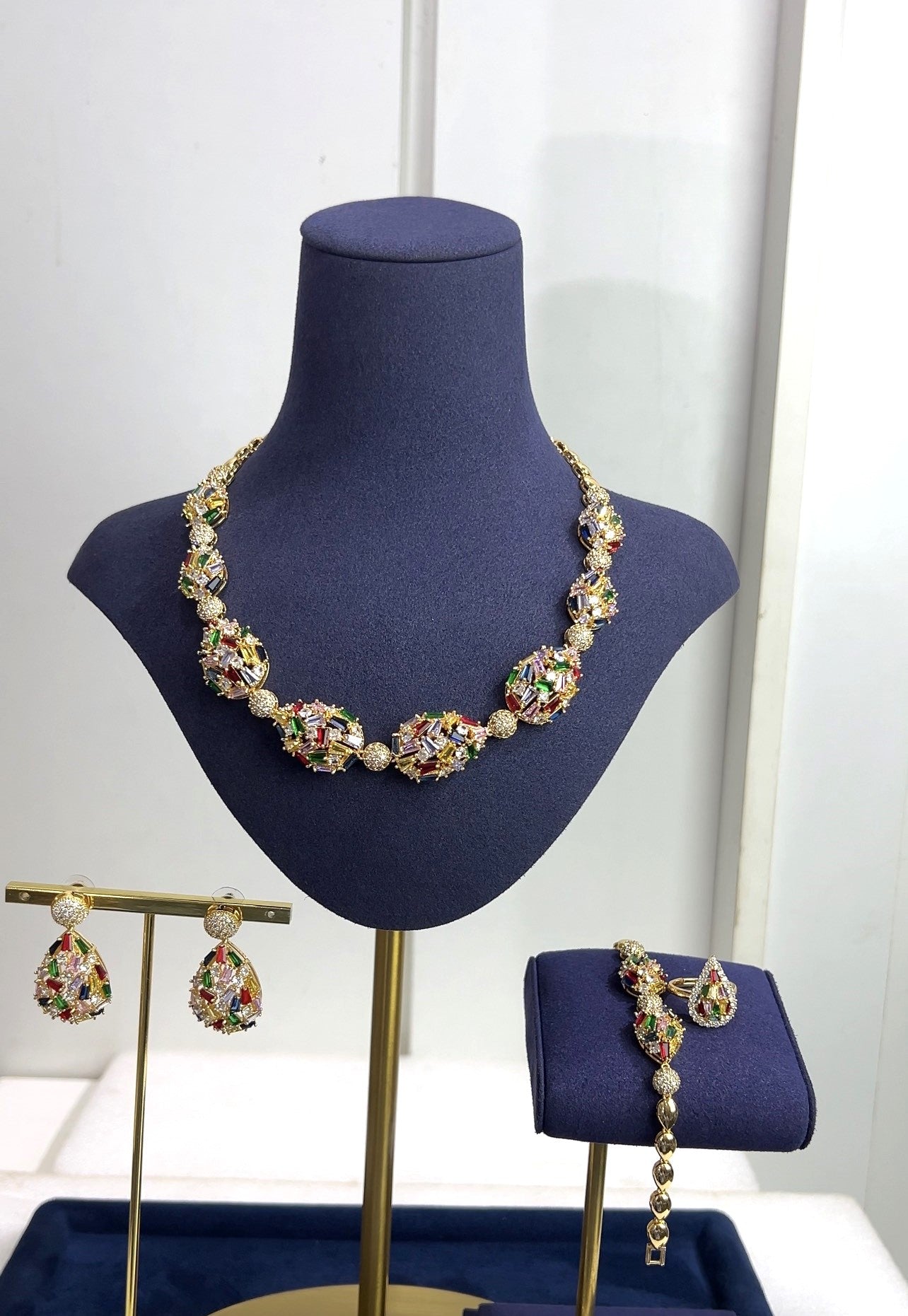 Jewelry set including necklace, earrings, and bracelet on a blue mannequin bust.