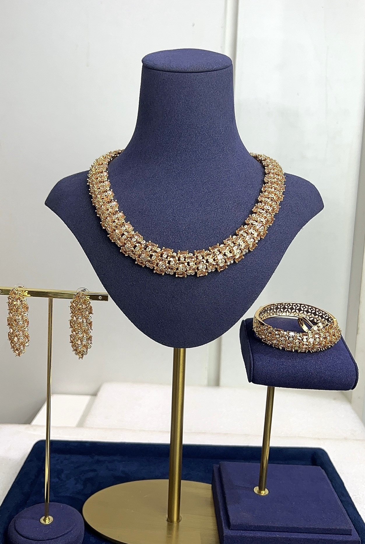 Jewelry set including a necklace, earrings, and bracelet on a blue mannequin bust.