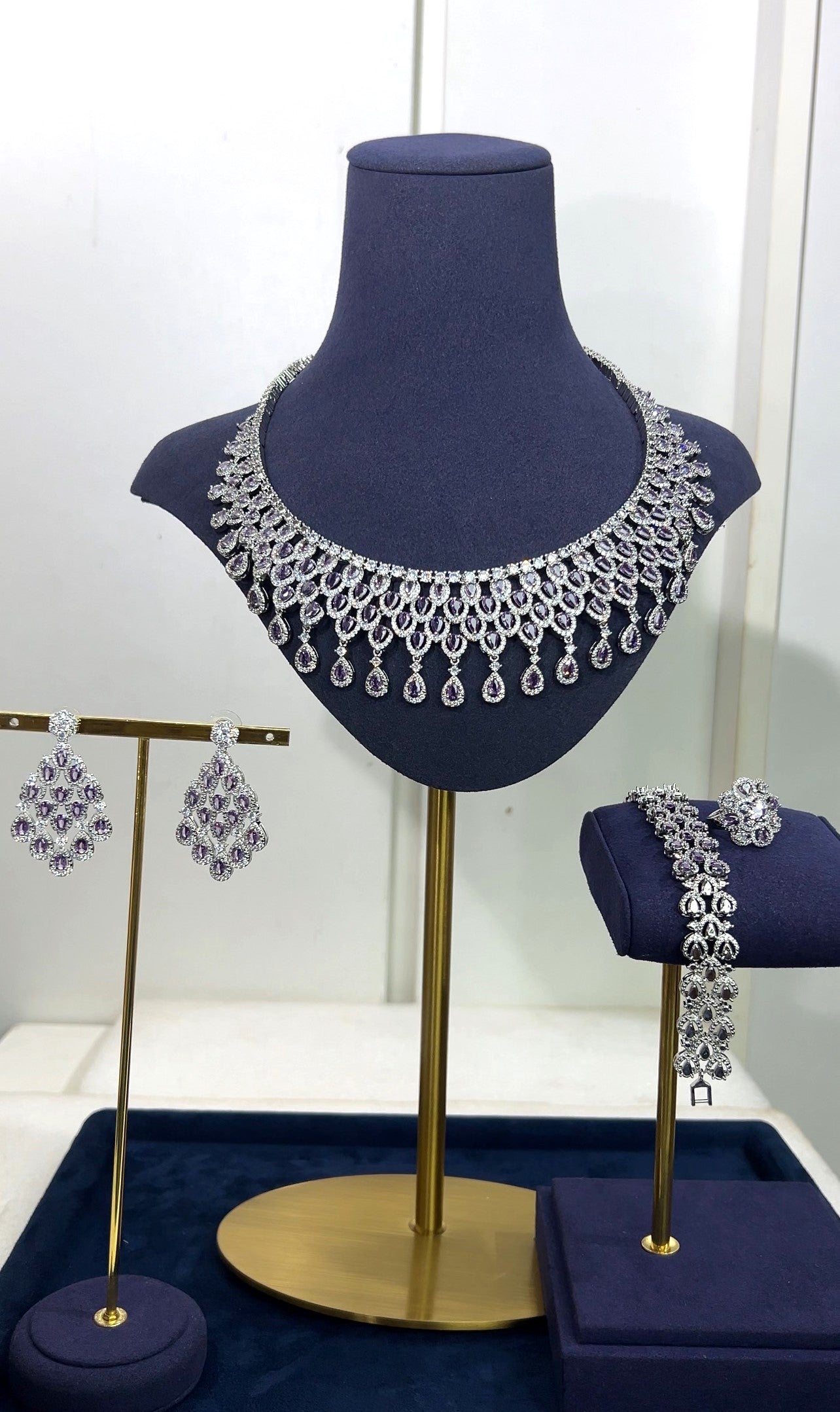 Jewelry set including necklace, earrings, and bracelet on a mannequin bust and stands.