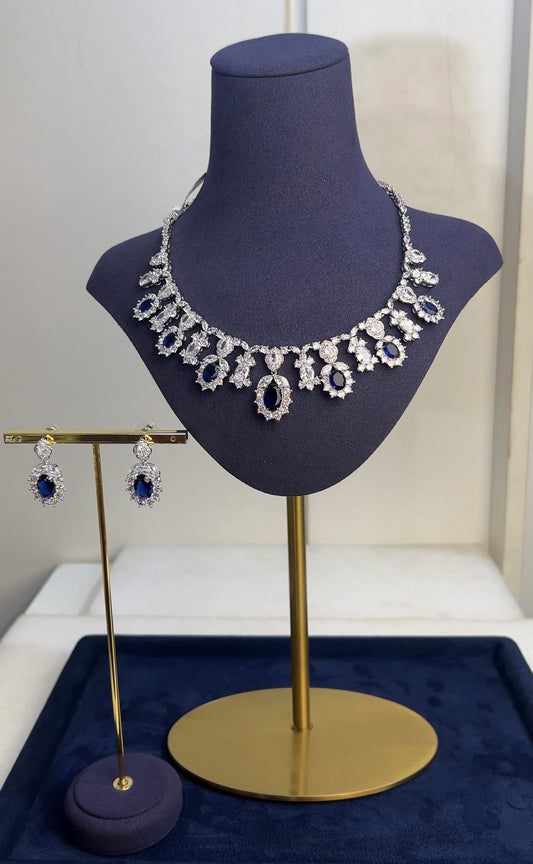 Jewelry set on a mannequin bust with a gold stand against a white background