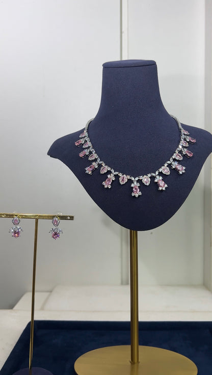 A luxury jewelry set displayed on a dark blue stand, featuring a necklace and Earrings