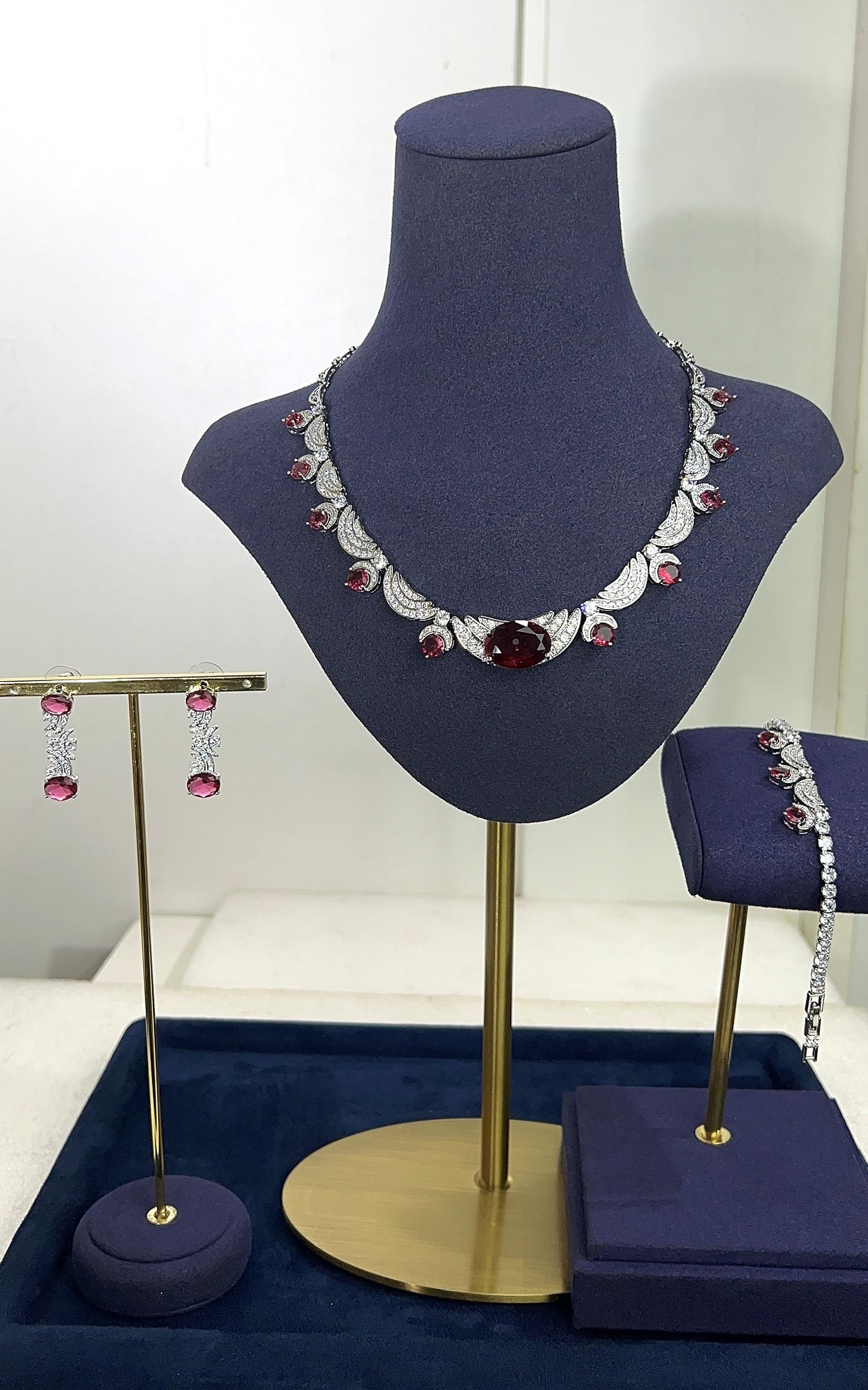 Jewelry set including a necklace and earrings displayed on a blue mannequin bust.