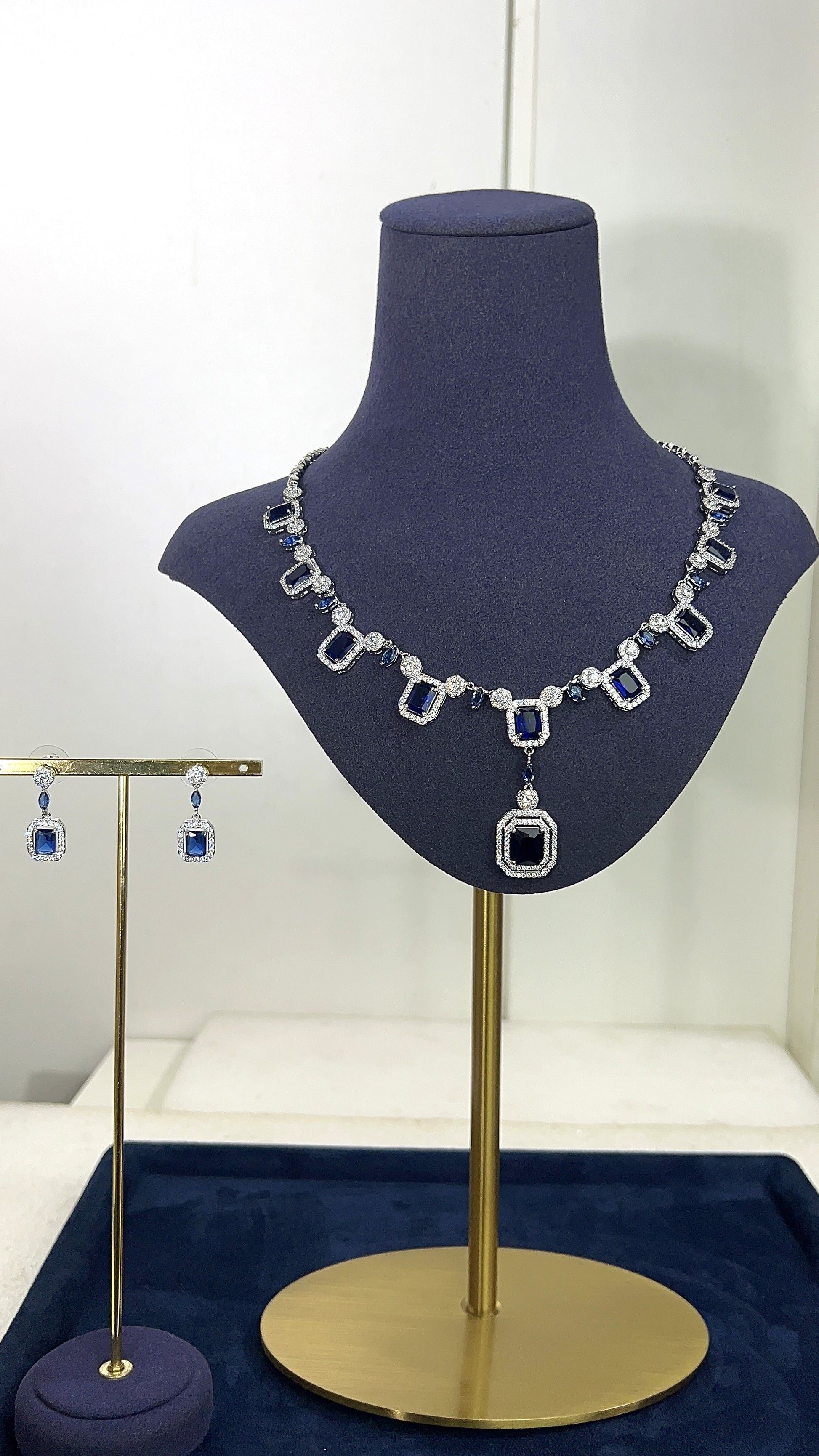 Necklace and earrings on a mannequin bust with a blue background