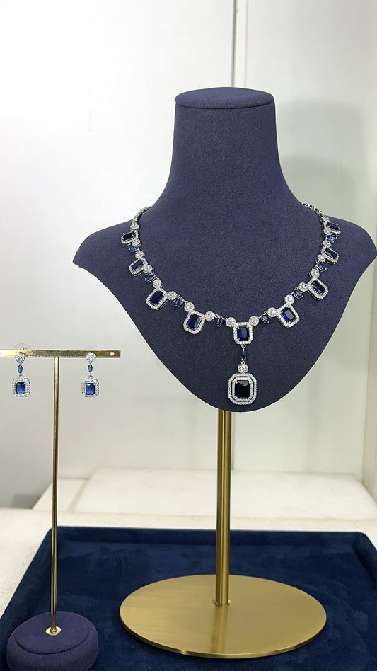 Necklace and earrings on a mannequin bust with a blue background
