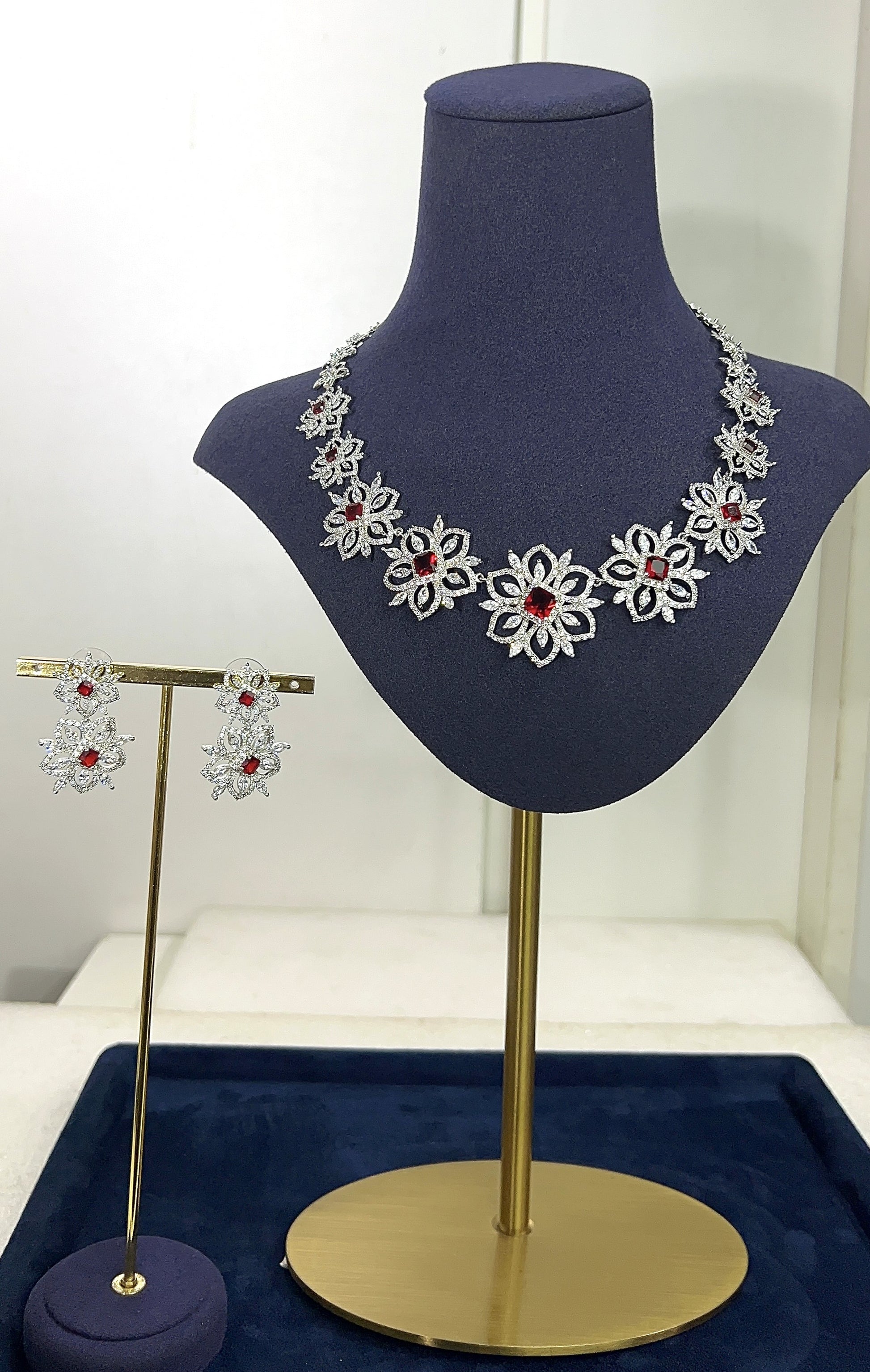 Jewelry set with necklace and earrings on a mannequin bust and stand.
