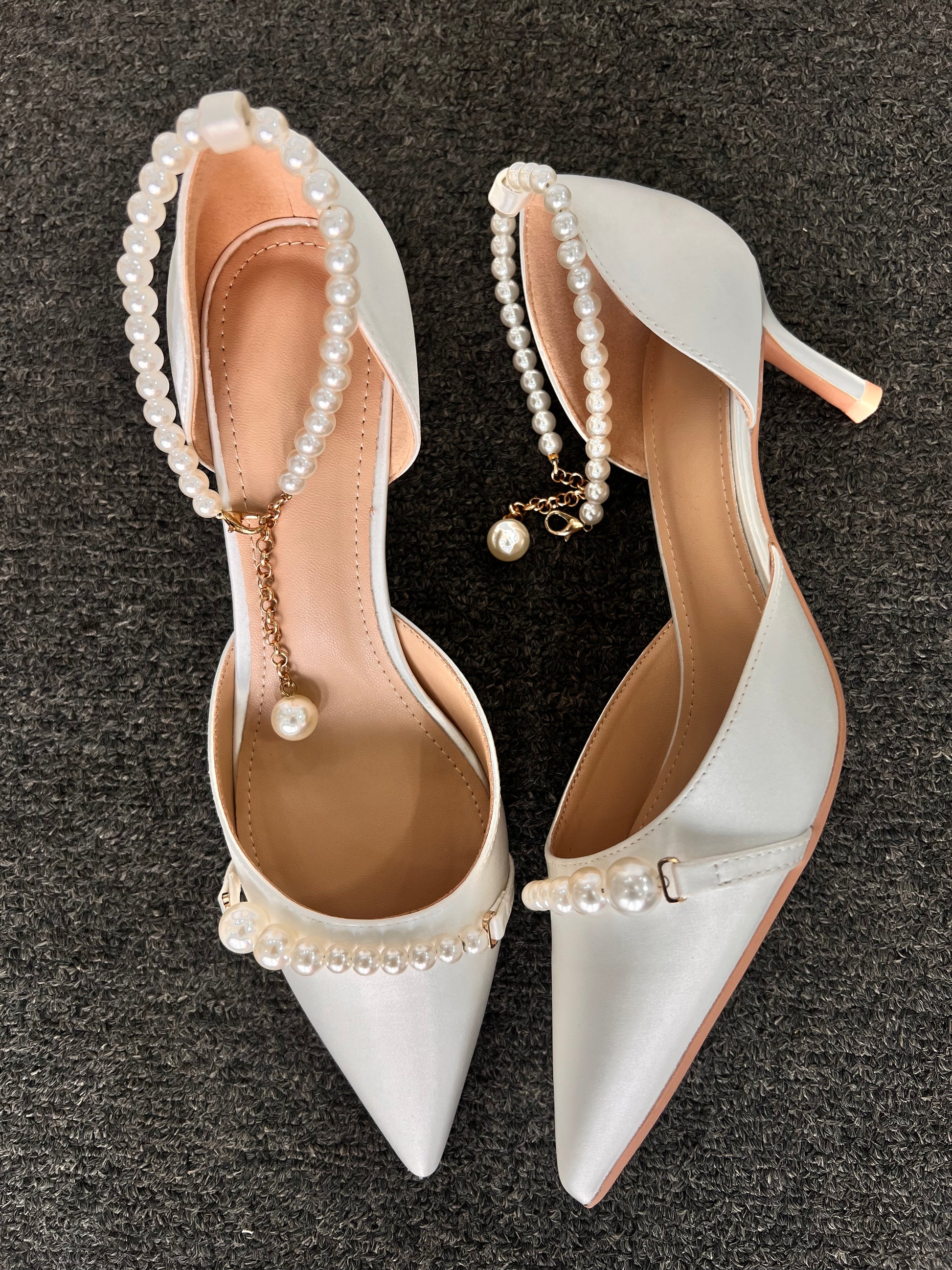 White high-heeled shoes with pearl embellishments 