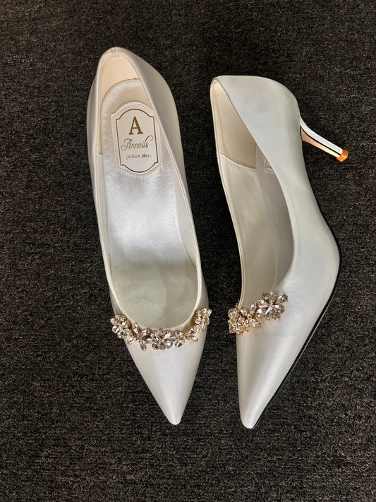 Pair of white high-heeled shoes with decorative embellishments With a slender, manageable kitten heel, these shoes offer a seamless transition from a formal ceremony to an evening reception without compromising on comfort.