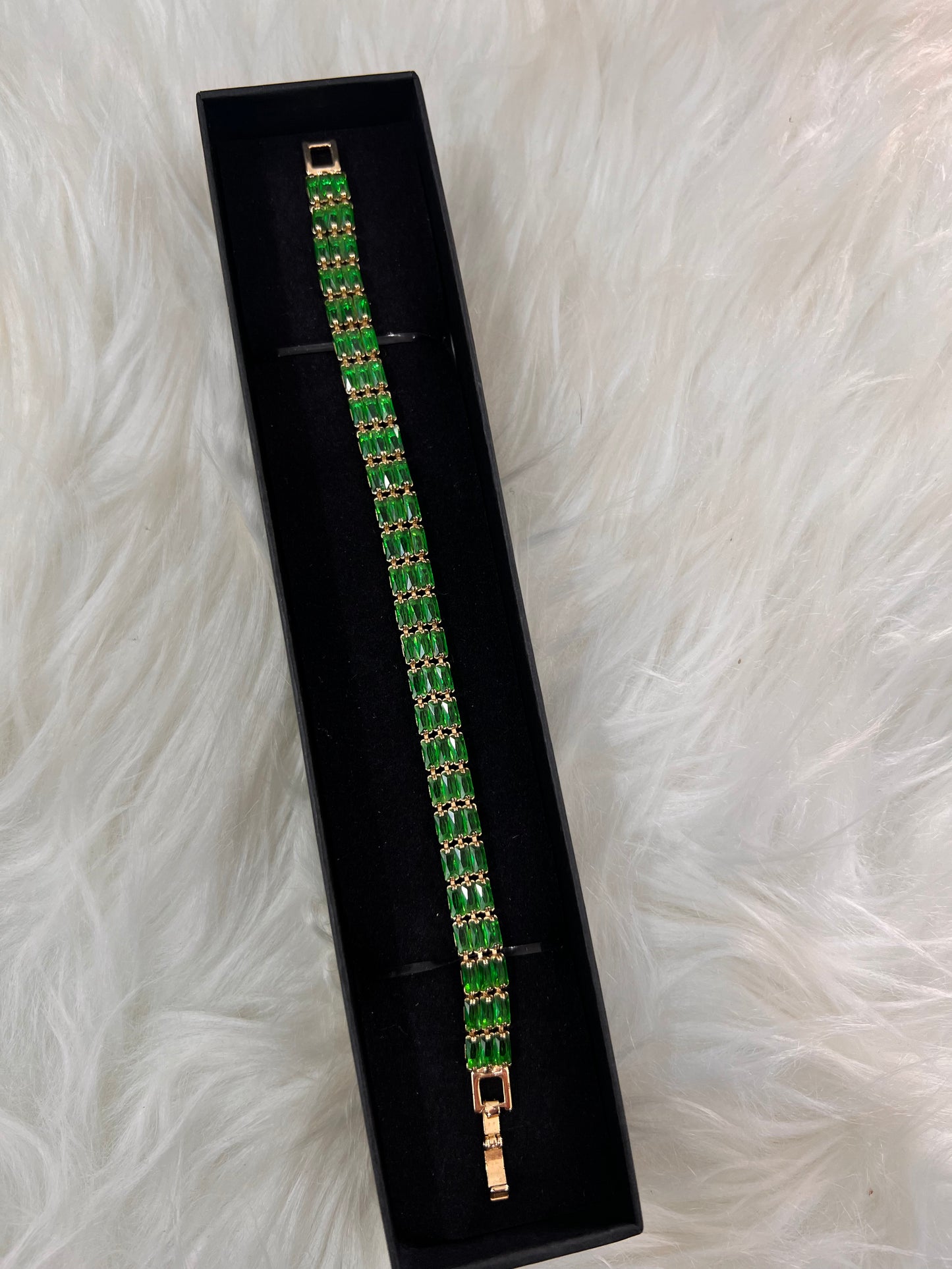 It features two continuous rows of emerald-green gemstones, creating a substantial and luxurious profile.